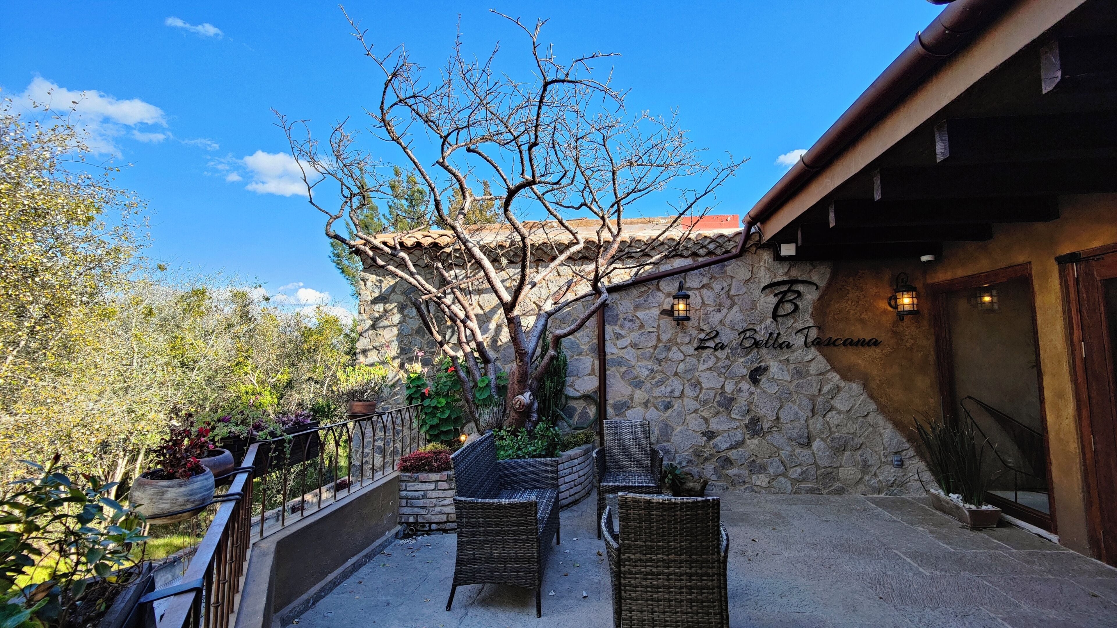 Ein Gebäude aus Stein mit Balkon, Korbmöbeln und Topfpflanzen.