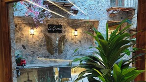 Um interior aconchegante com uma grande janela, paredes de pedra e uma planta em vaso.
