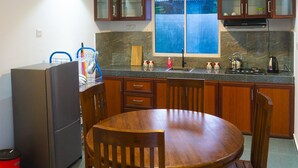 Una cocina con armarios de madera, encimera de granito, fregadero, estufa y mesa de comedor con sillas.