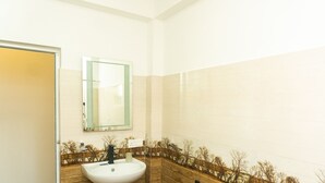 Un baño con un lavabo blanco, un espejo y una pared de azulejos con una escena de naturaleza.