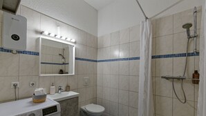 Une salle de bain équipée d’un lave-linge, de toilettes, d’un lavabo, d’un miroir et d’un espace douche.