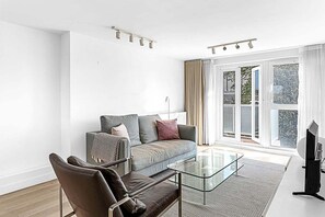 A modern living room with a sofa, armchair, and glass coffee table.