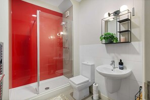 Bathroom features a glass-enclosed shower, toilet, and sink with a mirror.