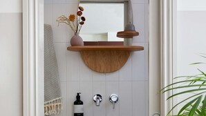 Een badkamer met een houten plank, een spiegel, een wastafel en een handdoekhouder.