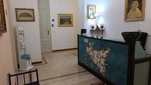 Zona de recepción con mostrador decorado como un mapa, obras de arte enmarcadas y dispensador de agua.