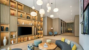 Una sala de estar moderna con un sofá curvo, una mesa de centro y un televisor. Hay estantes con objetos decorativos y una chimenea.