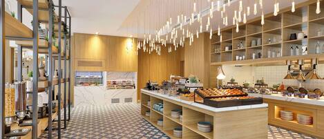 A modern kitchen with wooden shelves, hanging light fixtures, and a central island with food displays.