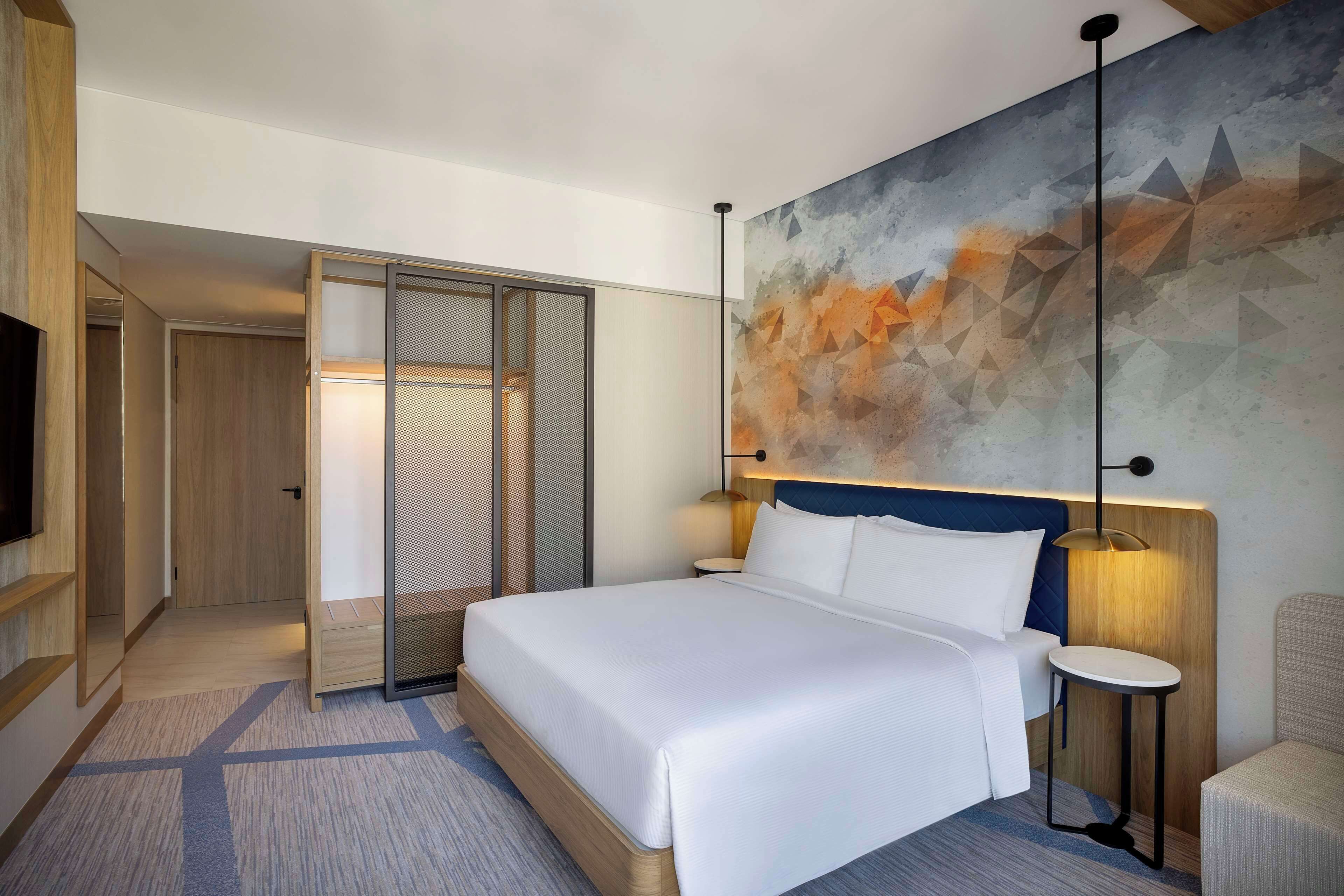Une chambre d’hôtel moderne dotée d’un grand lit, d’un coin salon, d’une télévision et d’une armoire.