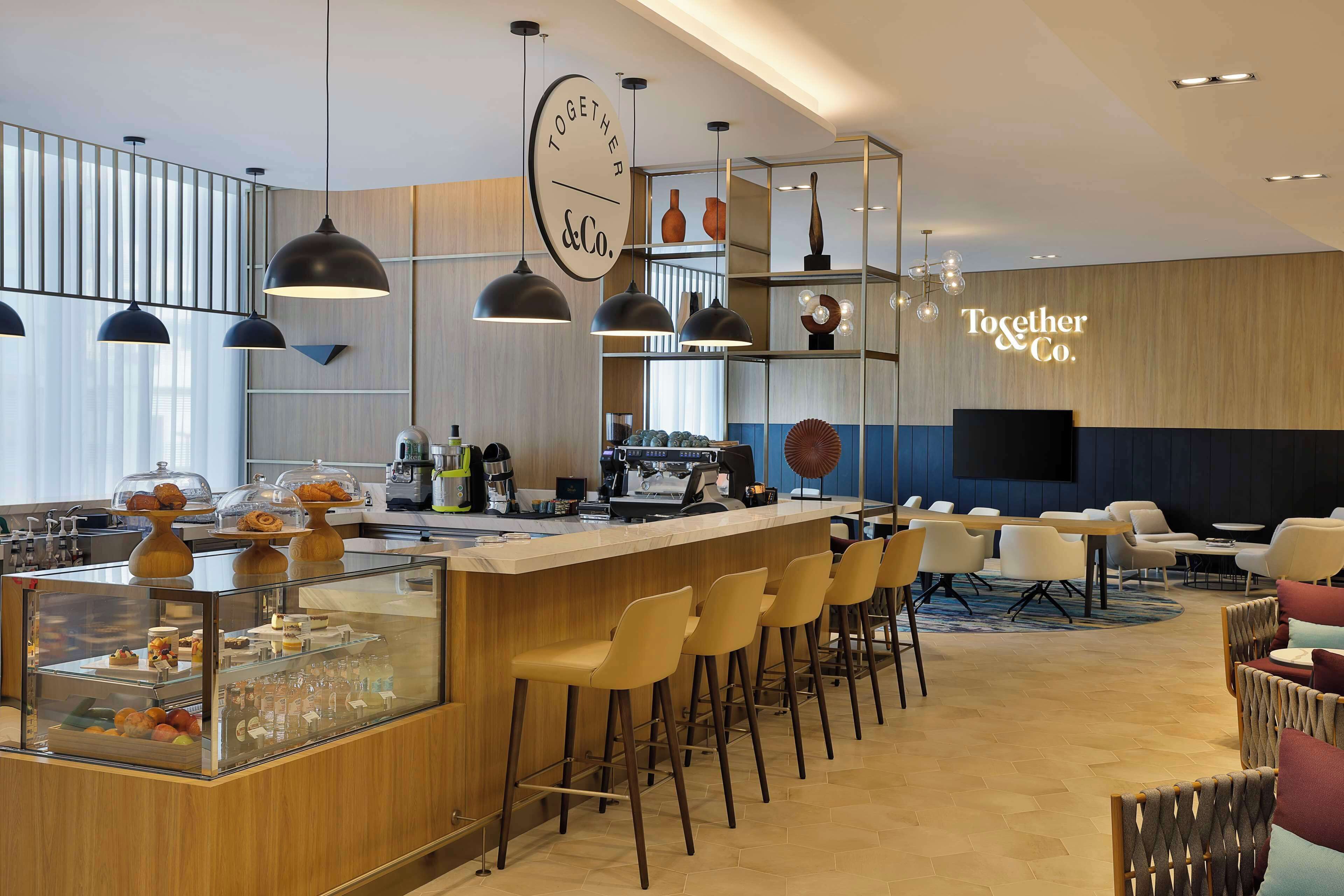 A modern bar area with a glass display case, bar stools, and overhead pendant lighting.