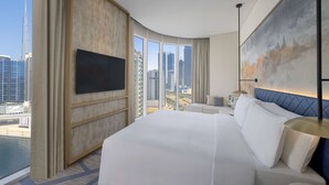 Habitación de hotel moderna con una cama grande, televisión de pantalla plana, vista a la ciudad y una pared de acento azul.