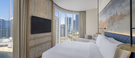 Une chambre d’hôtel moderne dotée d’un grand lit, d’un téléviseur à écran plat, d’une vue sur la ville et d’un mur d’accent bleu.