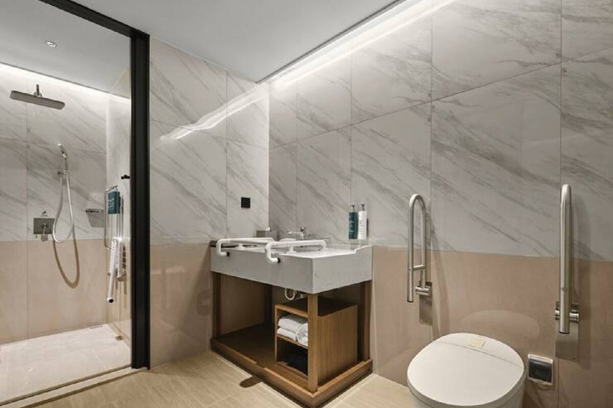 A modern bathroom with a glass-enclosed shower, a vanity with a sink, and a toilet.