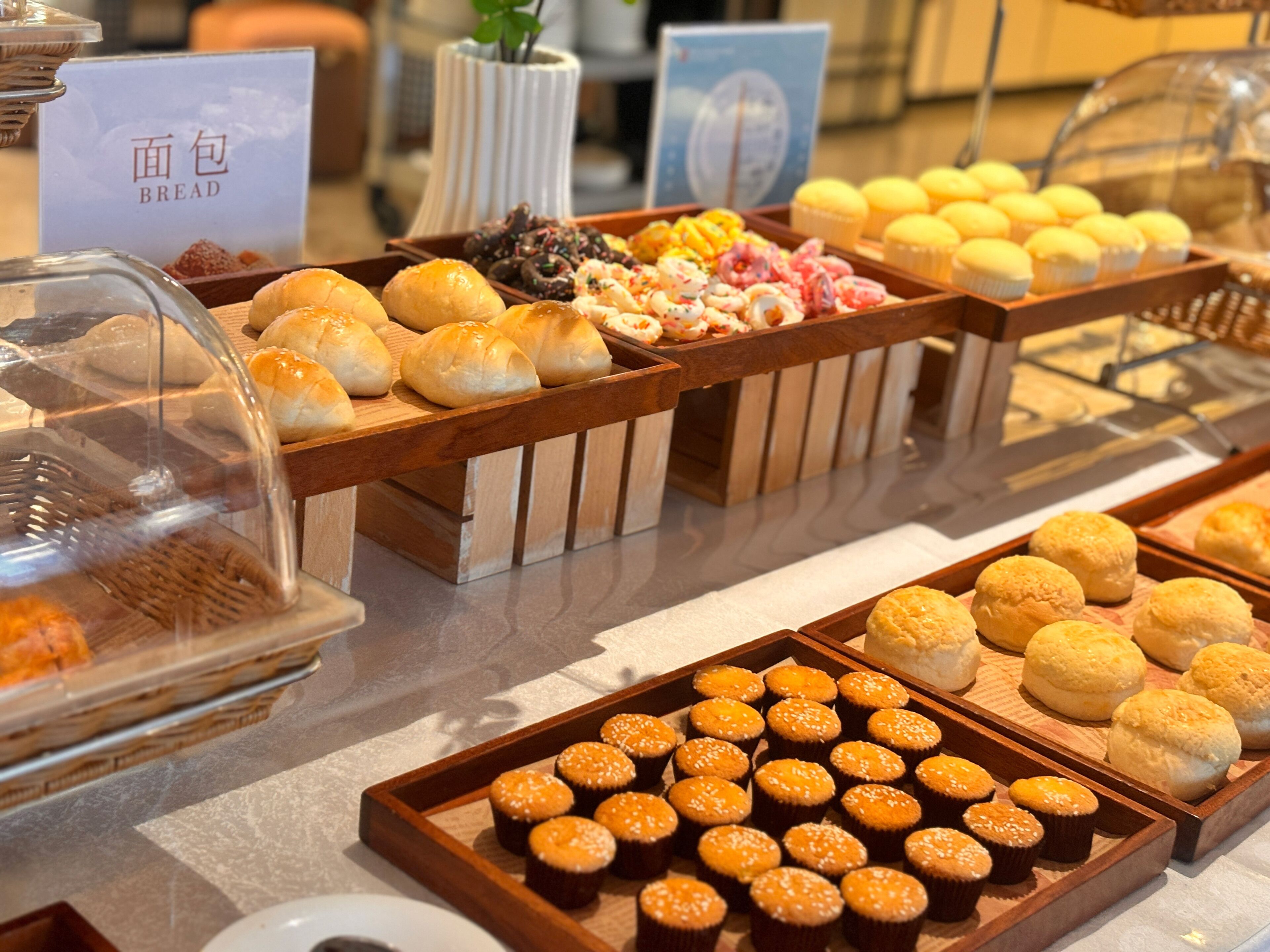 Un bufé con diversos productos de panadería, incluyendo pan, muffins y pasteles.