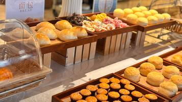 Un bufé con diversos productos de panadería, incluyendo pan, muffins y pasteles.