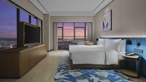 Una habitación de hotel moderna con una cama grande, televisión y vistas a la ciudad.