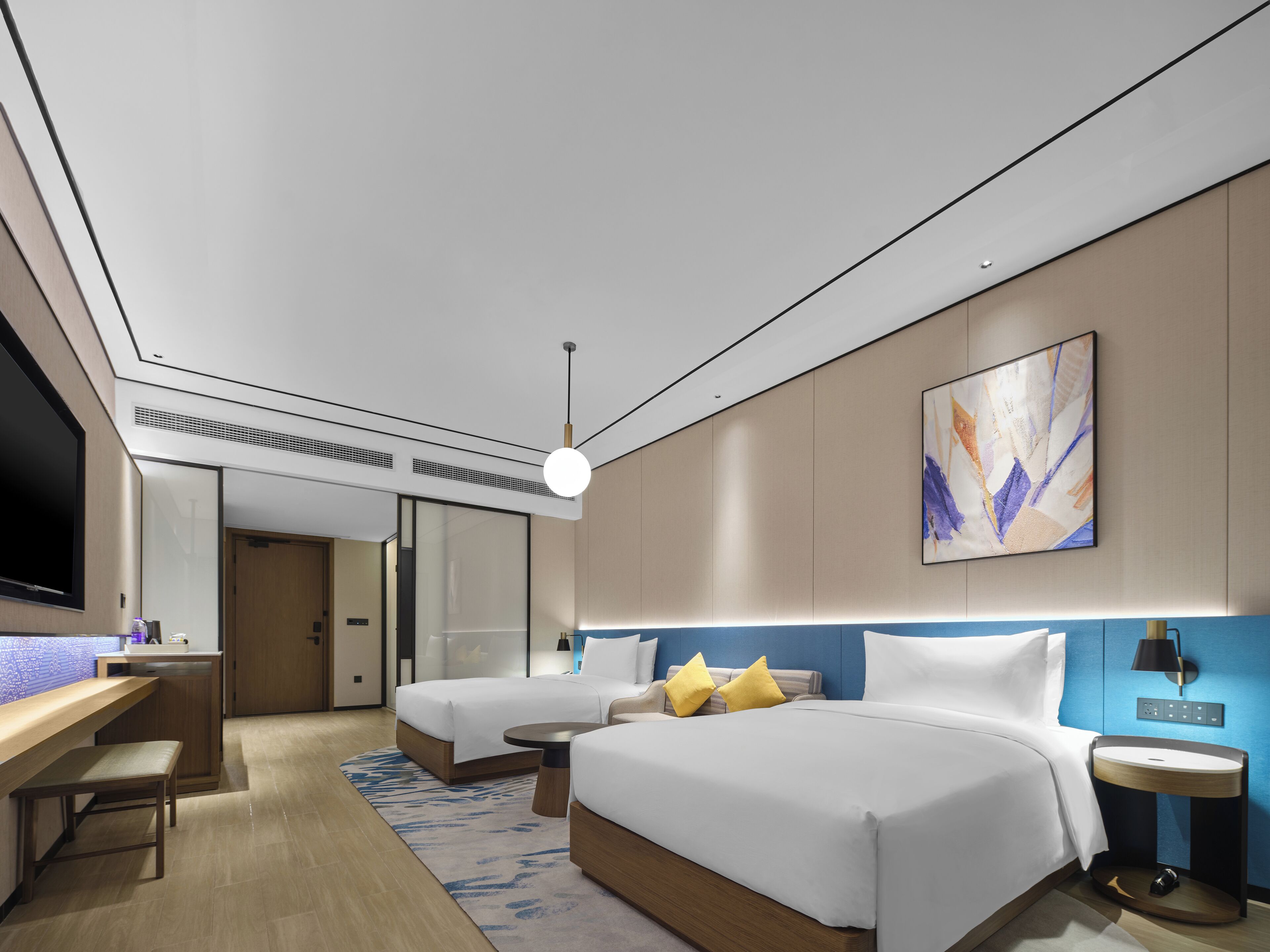 A modern hotel room with a large bed, a desk, and a television.