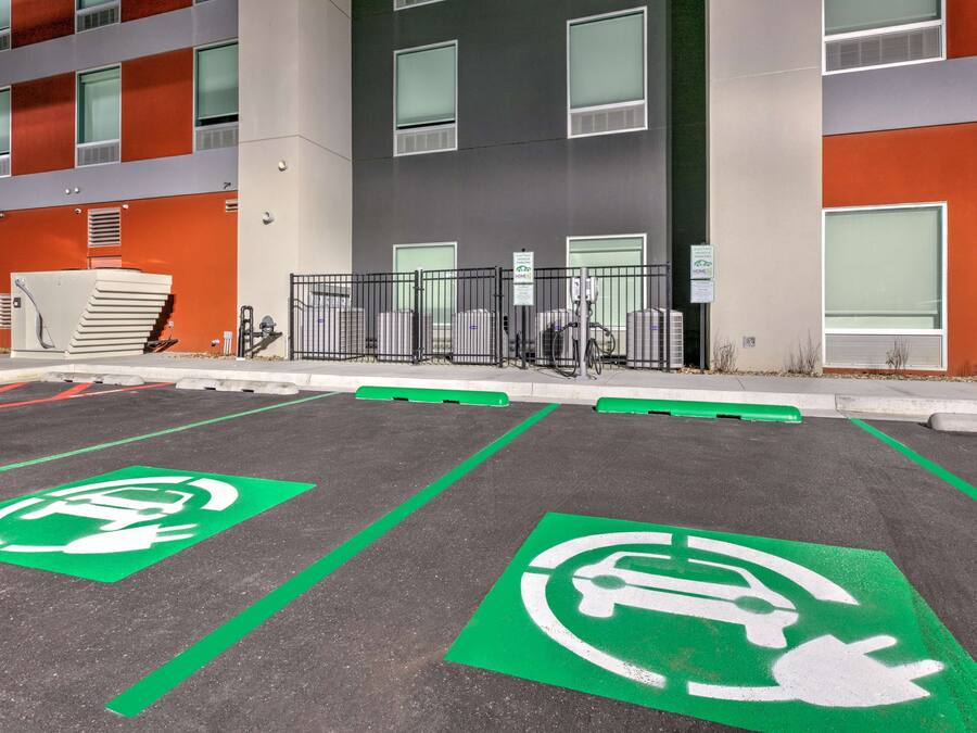 A parking area with electric vehicle charging stations and a building with orange and grey exterior walls.