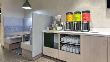 Una kitchenette moderna con una zona de estar integrada, una cafetera y un dispensador de agua.
