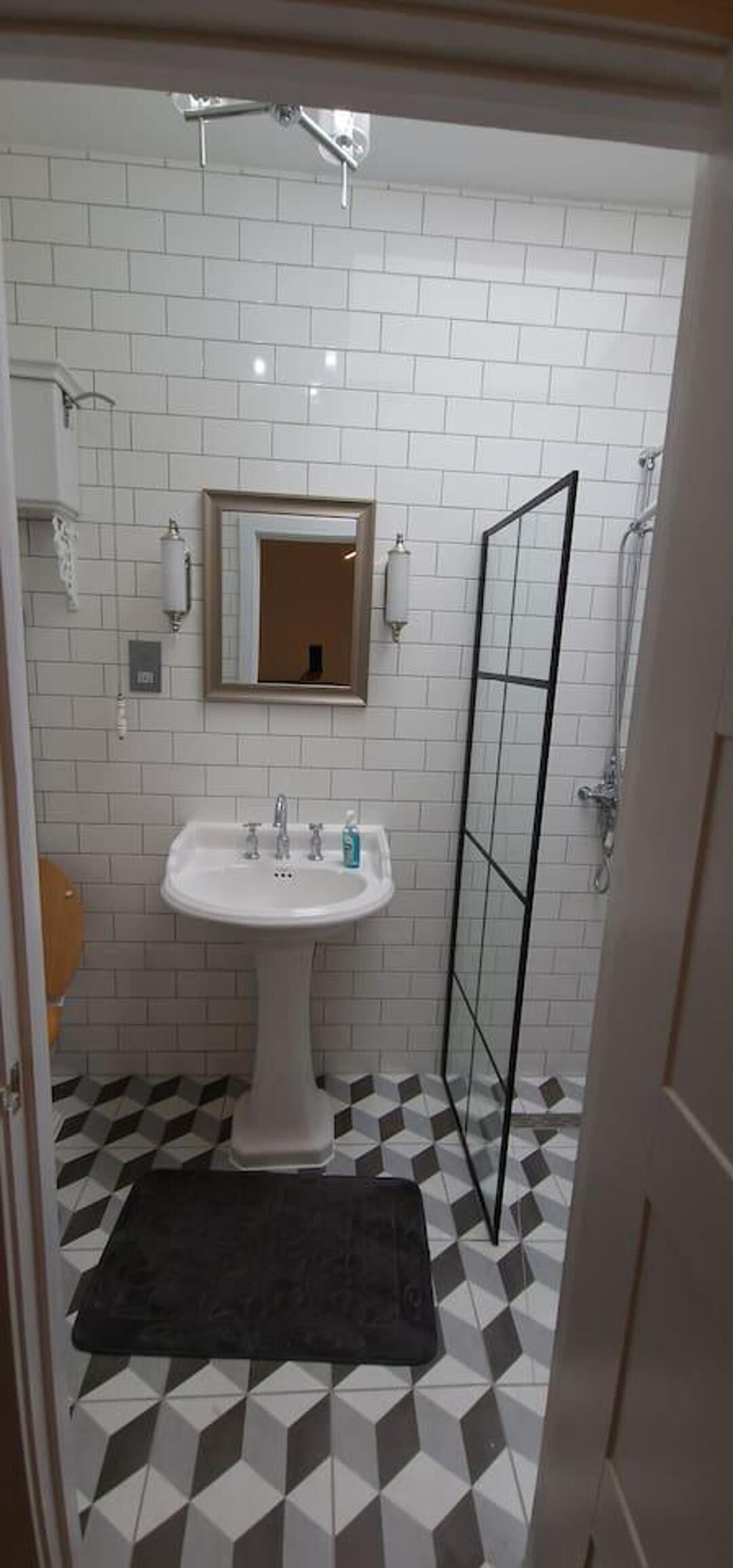 A bathroom with a white sink, a mirror, and a shower area.
