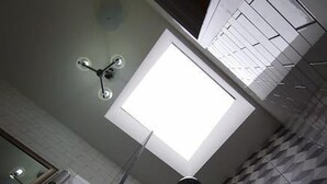 Ein Badezimmer mit Oberlicht, Dusche und einem Schachbrettmuster-Boden.