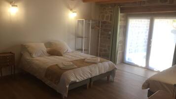 A bedroom with a bed, wooden headboard, bedside tables, a stone wall, and a sliding glass door.