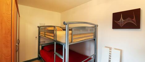 A bunk bed room with a wooden wardrobe and a wall-mounted artwork.