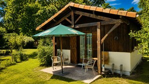 Una estructura de madera con un porche techado, dos sillas y una mesa.