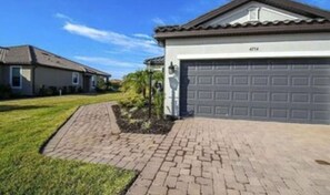 A residential house with a garage, paved driveway, and a well-maintained lawn.
