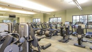 Een sportschool met diverse fitnessapparaten, waaronder loopbanden, krachttoestellen en gewichten.