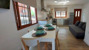 A compact kitchen with a dining area, a washing machine, and a sofa.