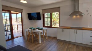 A modern kitchen with white cabinets, a wooden countertop, and a large wall clock.