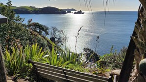 A bench overlooking a coastal view with a clear sky. - Seascape Point - Mahinepua Bay Clifftop Retreat (Mahinepua Bay)