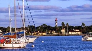 A marina with several sailboats docked, a lighthouse in the background, and buildings along the waterfront. - Tree Tops Everything is brand new (St. Augustine)