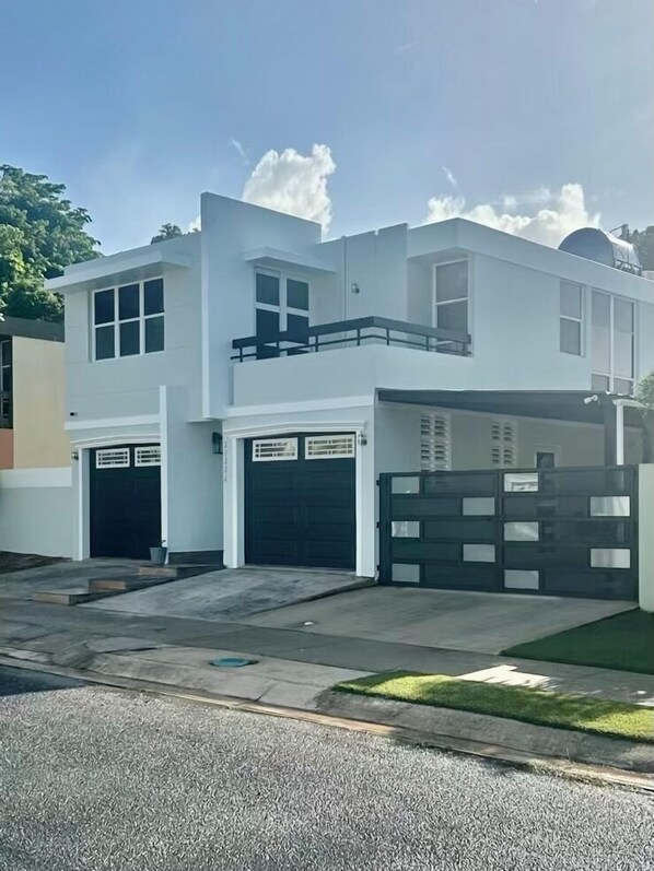 Una moderna casa a due piani con garage, balcone e vialetto recintato.