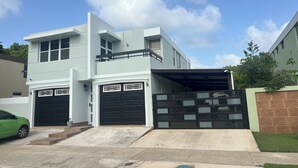 A modern two-story house with a garage, a covered driveway, and a small front yard.