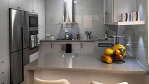 A modern kitchen with stainless steel appliances, a central island with seating, and a fruit bowl.