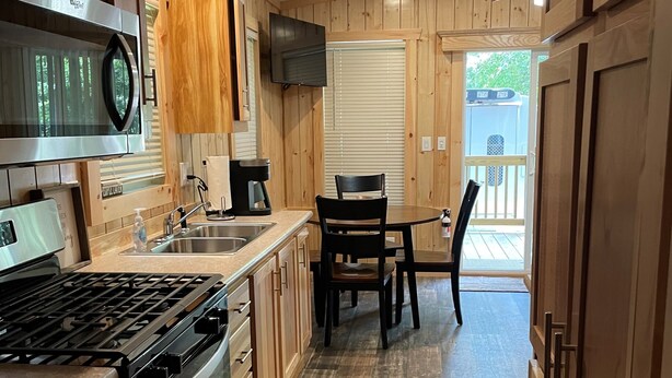 A modern kitchen with wooden cabinets, stainless steel appliances, and a dining area with a table and chairs.