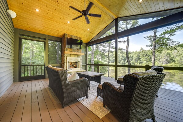 Une terrasse en bois avec des meubles en osier et une cheminée.