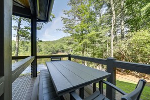 Une terrasse en bois avec une table et des bancs, donnant sur une zone boisée.
