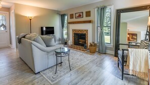 A living room with a sofa, a fireplace, a television, and a large mirror. - Tranquil Cottage in Virginia Countryside w/ Pond! (Midlothian)