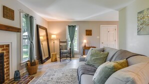A living room with a fireplace, a sofa, a zebra-patterned chair, and a large mirror. - Tranquil Cottage in Virginia Countryside w/ Pond! (Midlothian)