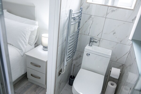 Une petite salle de bain moderne équipée de toilettes, d’un bidet et d’une table de chevet avec une lampe.