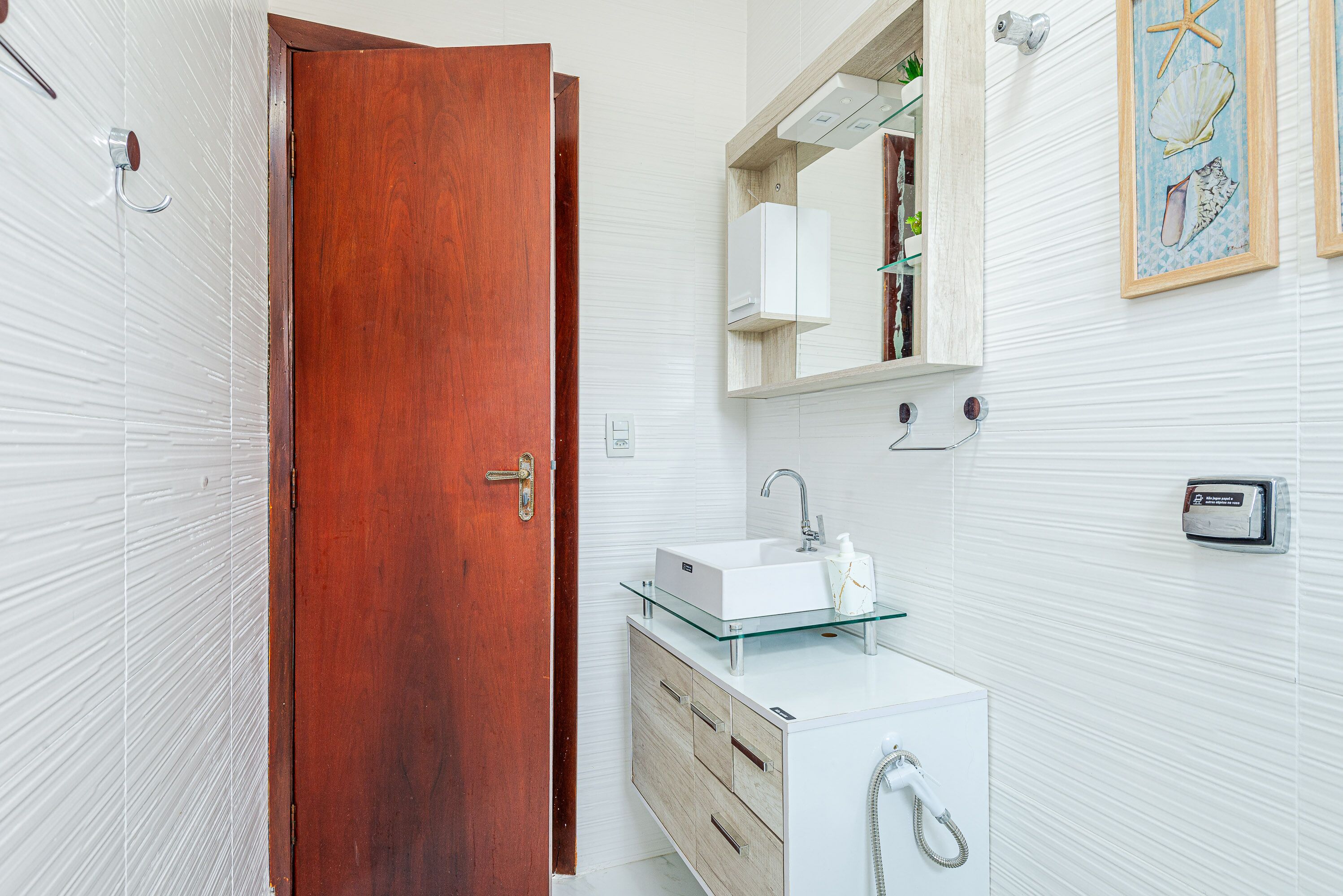 A bathroom with a wooden door, a glass sink, a mirror, and a wall-mounted heater.