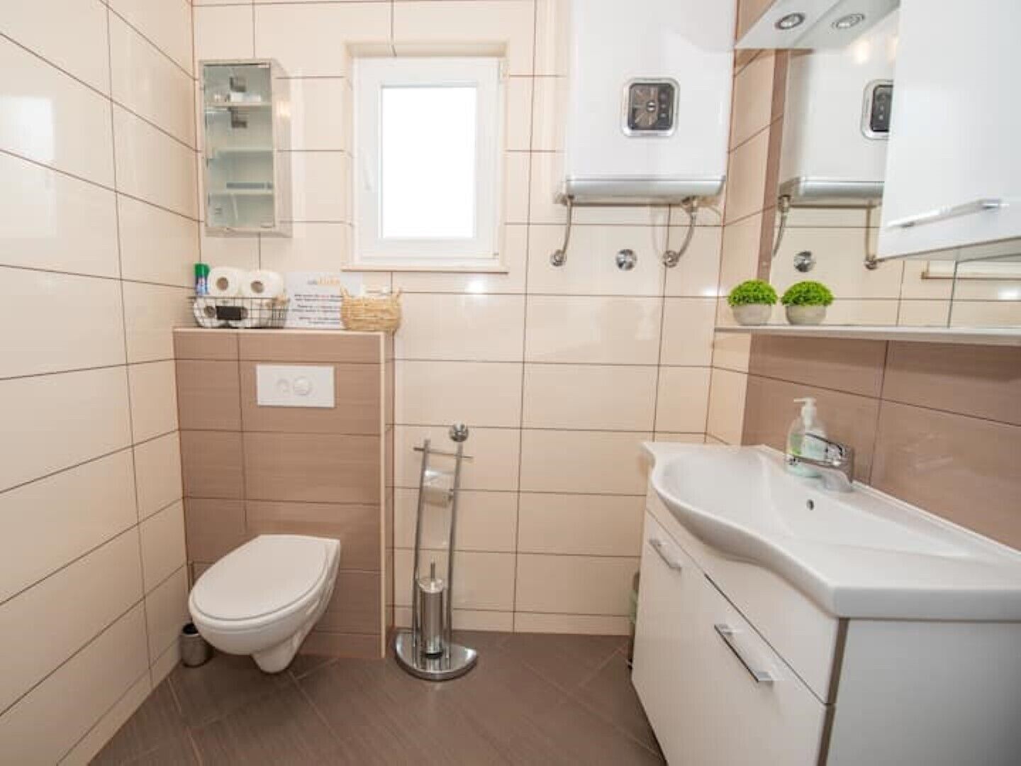 Une petite salle de bain comprenant des toilettes, une douche, un lavabo et un miroir.