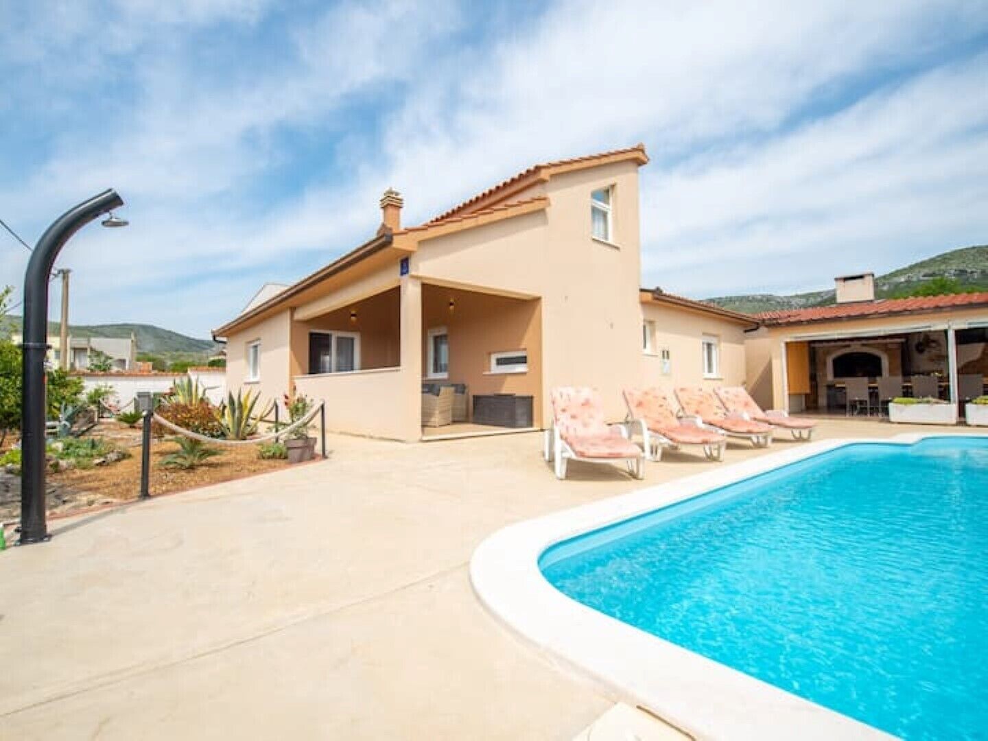 A two-story building with a swimming pool, lounge chairs, and a covered patio area.