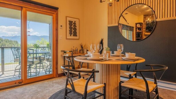 Un espace repas comprenant une table ronde, des chaises, un miroir et une vue sur l’extérieur.