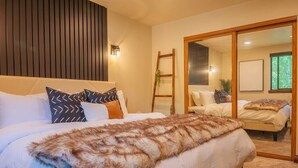 Une chambre à coucher avec un grand lit, une tête de lit en bois, un miroir et une échelle.
