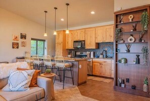 Une cuisine moderne avec des meubles en bois, un îlot central, des luminaires suspendus et un coin repas avec des chaises.