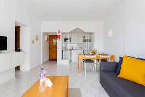 A modern living room with a sofa, coffee table, and a dining area with a table and chairs.