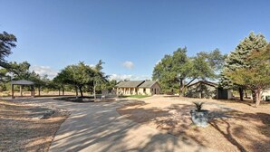A residential area with a house, a covered pavilion, and a paved driveway. - Secluded Hill Country Retreat: Bunkhouse and Spa (Austin)
